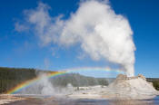 Image of Castle Geyser erupting as rainbow forms, Yellowstone National Park.